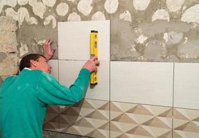 Worker puts tiles on the wall. Finishing works, blurred focus. The technology of laying tile photo