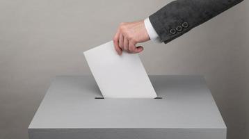 Gray ballot box. Presidential and parliamentary elections. The voter throws the ballot into the ballot box photo