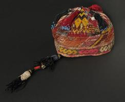 colorful traditional asian skullcap hat with pigtails on a dark background