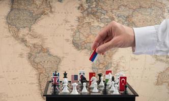 Politician's hand moves a chess piece with a flag. Conceptual photo of a political game. retaliatory move of Russia