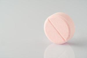 pink medical ascorbic pill on a light background with reflection photo