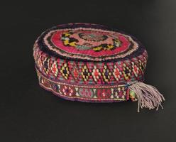 colorful traditional asian skullcap hat with pigtails on a dark background
