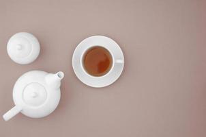 White ceramic teapot with cup on brown background photo