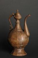 ancient oriental metal teapot on dark background. antique bronze tableware photo