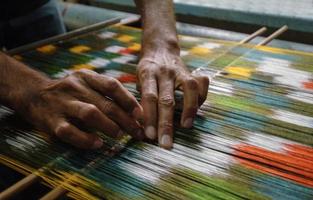 weaving and manufacturing of handmade carpets closeup. man's hands behind a loom photo