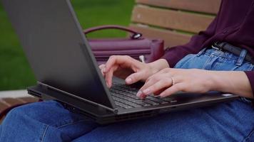 Close up typing woman hands laptop outdoor park. video