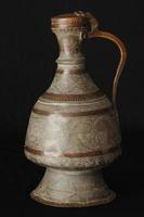 ancient oriental metal jug on dark background. antique bronze tableware photo