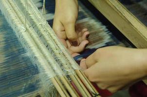 tejido y fabricación de tela hecha a mano de cerca. las manos de las mujeres detrás de un telar hacen tela foto