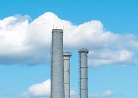 Pipes of an industrial enterprise against a blue sky with clouds. Chimney without smoke photo
