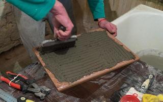 Worker applies cement adhesive on the tiles. Finishing works, blurred focus. The technology of laying tile photo