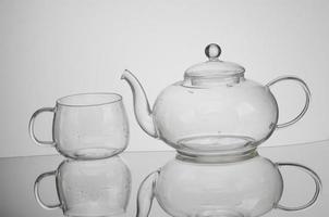 transparent glass teapot and tea cup with reflection photo