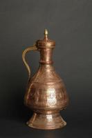 ancient oriental metal jug on dark background. antique bronze tableware photo