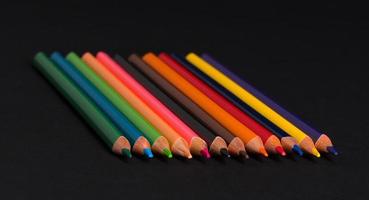 conjunto de lápices de colores sobre un fondo negro aislado. De vuelta a la escuela foto
