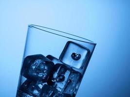 top of a glass of water with ice cubes on a light blue background