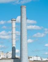 Pipes of an industrial enterprise against a blue sky with clouds. Chimney without smoke photo