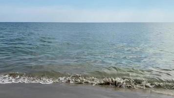 O ataque das ondas do mar à praia ocorre de relaxamento sonoro e tranquilo. a vista para o mar sob o céu. video
