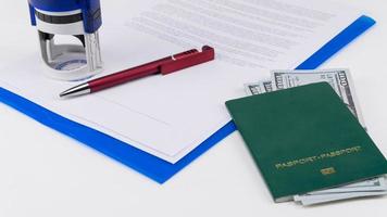 green passport with US dollars on the background of documents and contract. Concept briber and corruption photo