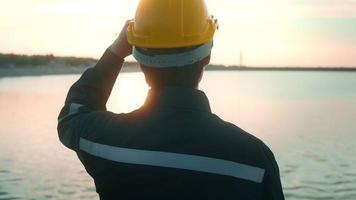 A male engineer wearing a protective helmet at sunset. video