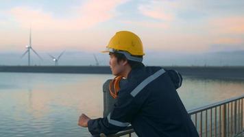 een mannelijke ingenieur die een beschermende helm draagt bij zonsondergang. video