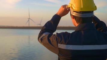 een mannelijke ingenieur die een beschermende helm draagt bij zonsondergang. video