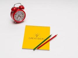 alarm clock with notepad and colored pencils on white background, isolated. back to school. great ideas photo