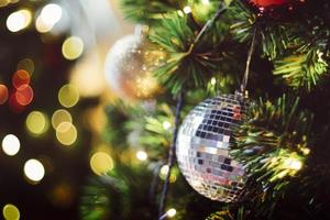 árbol de navidad decorado en el fondo borroso de año nuevo multicolor. adorno de navidad sobre fondo de madera con copos de nieve, tarjeta de felicitación feliz navidad y feliz año nuevo. foto