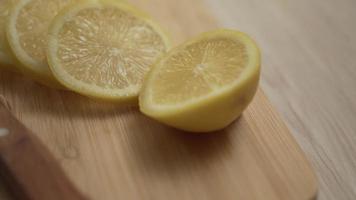 Cutting lemon fruit into slices on a wood cutting board with a knife
