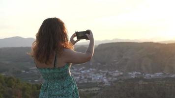 jovem tirando uma foto de paisagem ao pôr do sol video