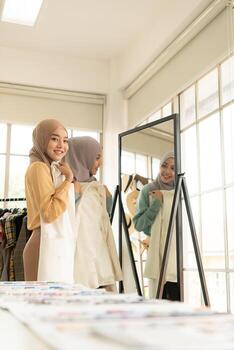 ambas mujeres musulmanas tienen un pequeño negocio en sus propios hogares. es el diseño y confección de ropa. foto