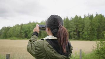 vista posterior de una mujer asiática tomando una foto en una granja, saliendo en una granja, usando un teléfono inteligente para tomar una foto y tomando aire fresco el fin de semana, relajando el estado de ánimo en un concepto de granja video