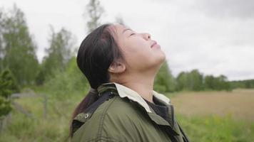 gros plan sur une femme asiatique debout et respirant profondément dans une ferme. voir une belle vue et prendre l'air le week-end, des ambiances relaxantes dans un concept de ferme video