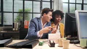 Young African American female worker sits, works with computer, brainstorming, talking, and discussing with Caucasian male colleague and partnership about business jobs in workspace office company. video