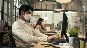 Two coworkers team, face mask colleagues working in new normal office. COVID-19 protection by cleared partition, business workplace office, social distancing for pandemic health, disease prevention. video