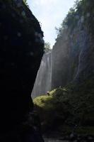 paisaje de la cascada desde el fondo con agua salpicada. tema de fondo tropical y de verano. ubicación en la cascada tumpak sewu, indonesia foto