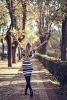 Young blonde woman walking in the street raising her arms photo