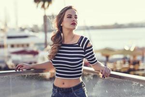 Blonde woman, model of fashion, sitting in urban background. photo