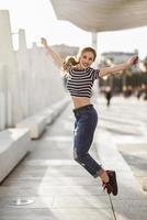Funny blonde woman jumping in urban background.