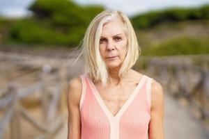 Eldery female walking along a wooden path near the beach., wearing a nice orange dress. photo