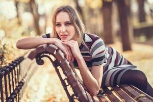 Young blonde woman sitting on a bench of a park photo