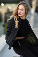 hermosa joven con chaqueta negra sentada en la calle. foto