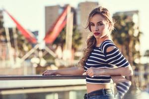 Blonde woman, model of fashion, sitting in urban background. photo