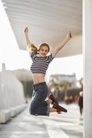 Funny blonde woman jumping in urban background. photo