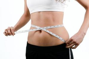 young woman measuring waist with tape on white background photo