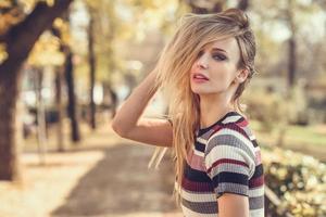 Young blonde woman standing in the street moving her hair photo