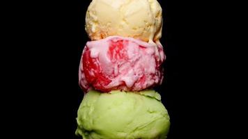 lapso de tiempo, fusión de tres sabores de helado en un cono. el agua de helado fluye del cono. sobre el fondo negro. video