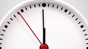 Zeitraffer, weiße Uhr mit einem kurzen Zeiger und einem langen Zeiger, der auf die Zahl Zwölf zeigt. die Bewegung der Uhrzeiger verging schnell. auf dem zweifarbigen Hintergrund. video