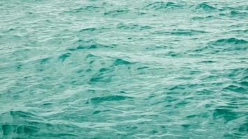 vue de dessus, les vagues d'eau à la surface de la mer coulent avec le vent qui souffle. la lumière du soleil frappe la mer vert émeraude. video