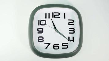 l'orologio da parete bianco segna l'ora alle 11. il tempo trascorse lentamente in una giornata su fondo bianco. video