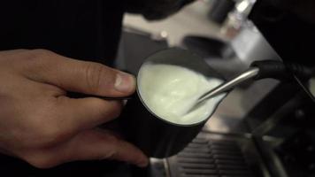 camarero humeando leche en la máquina de café. de cerca video
