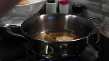 el chef saca manzanas preparadas en masa, fritas en una sartén con aceite hirviendo. video